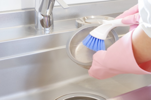 キッチンの排水口つまりを予防するための掃除をする人の手